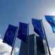 EU flags flying outside tall building