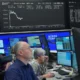 Traders monitor stock market data on multiple screens.