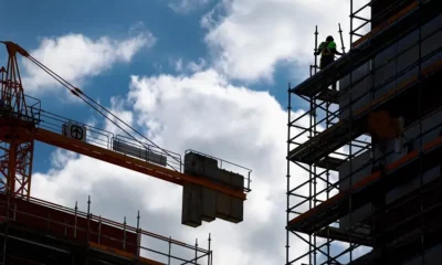 Construction site with crane and worker on scaffolding.