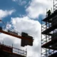 Construction site with crane and worker on scaffolding.