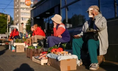 Street vendors selling vegetables at outdoor market.