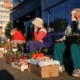 Street vendors selling vegetables at outdoor market.