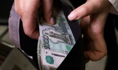 Hands holding envelope with Russian rubles inside.