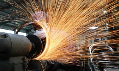 Worker grinding metal, sparks flying.