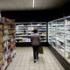 Person shopping in a supermarket aisle with freezers.