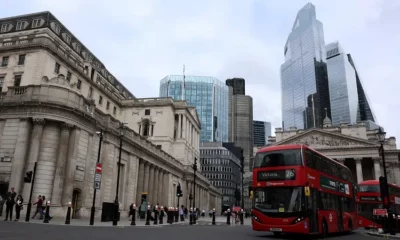 London street with red buses and tall buildings.