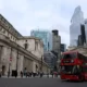 London street with red buses and tall buildings.