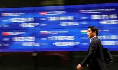 Man walks past stock market index board.