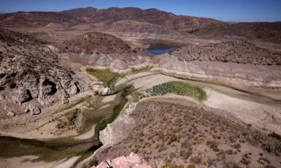 Dried reservoir surrounded by arid, mountainous landscape.