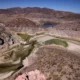 Dried reservoir surrounded by arid, mountainous landscape.