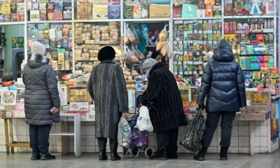 Shoppers at a market stall buying goods.