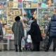 Shoppers at a market stall buying goods.