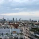 Milan skyline with statue foreground, cloudy sky.