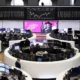 Stock exchange trading floor with data screens.