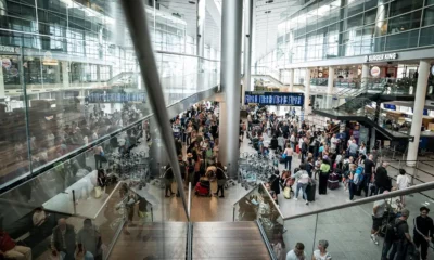 Busy airport terminal with crowds and luggage trolleys.