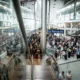 Busy airport terminal with crowds and luggage trolleys.