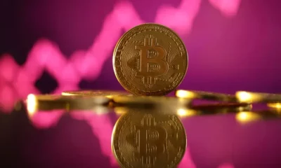 Bitcoin coin with pink stock chart background.