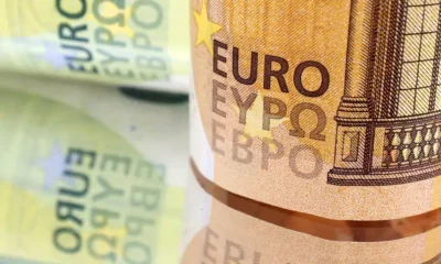 Close-up of Euro banknotes on reflective surface.