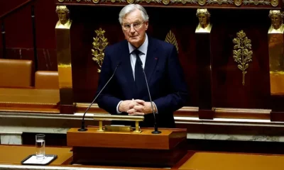 Man speaks at podium in formal setting.