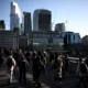 Crowded walkway with London skyscrapers in background.