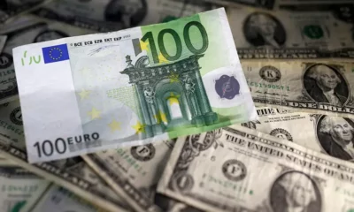 Euro note on pile of US dollars.