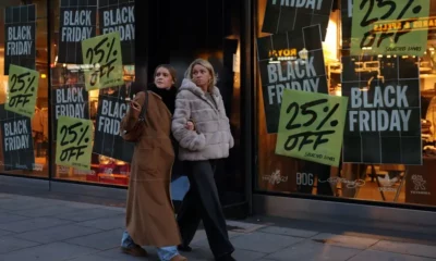 Women walking past Black Friday sale signs.