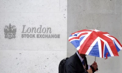 Person with Union Jack umbrella outside London Stock Exchange.