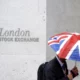 Person with Union Jack umbrella outside London Stock Exchange.