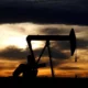 Oil pumpjack silhouetted against sunset sky