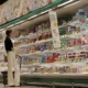 Woman shopping in supermarket dairy aisle.