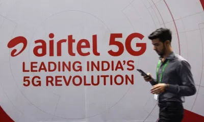 Man walking past Airtel 5G advertisement banner.