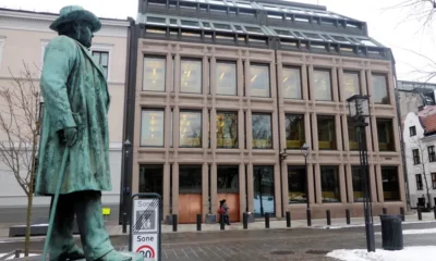 Statue outside modern building in snowy urban setting.