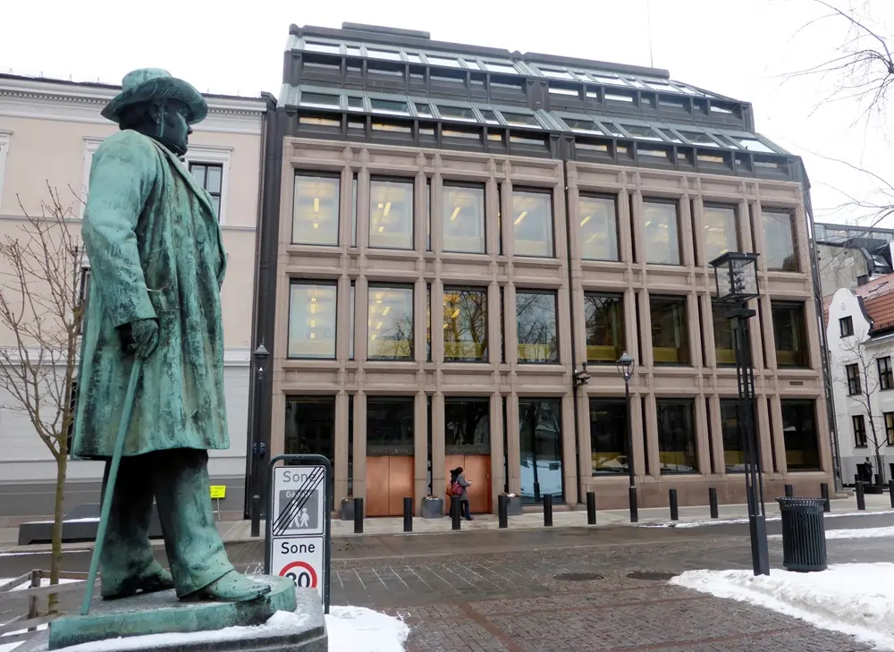 Statue outside modern building in snowy urban setting.