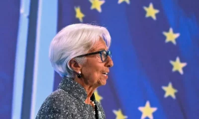 Person speaking in front of EU flag stars.