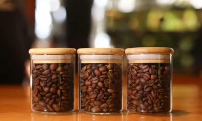 Three jars filled with coffee beans on table.