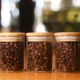 Three jars filled with coffee beans on table.