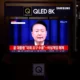 Samsung QLED TV showing news broadcast.