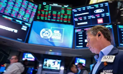 Stock trader on exchange floor with digital screens.