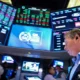 Stock trader on exchange floor with digital screens.