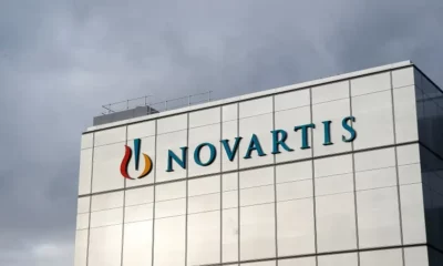 Novartis building with logo against cloudy sky.