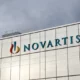 Novartis building with logo against cloudy sky.