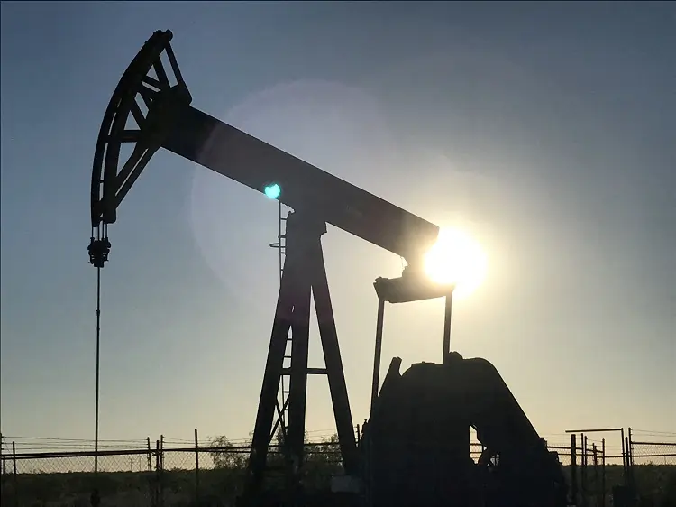 Oil pumpjack silhouetted against setting sun