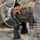 Engineers inspecting aircraft engine in workshop