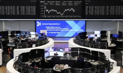 Traders at Frankfurt stock exchange, large screens visible.