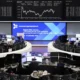 Traders at Frankfurt stock exchange, large screens visible.