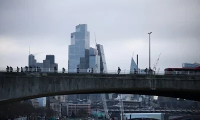 City skyline view with bridge foreground, cloudy sky.