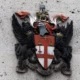 City of London coat of arms on stone wall.