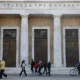 People walk past Bank of Greece building.