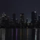 City skyline illuminated at night over water reflection.