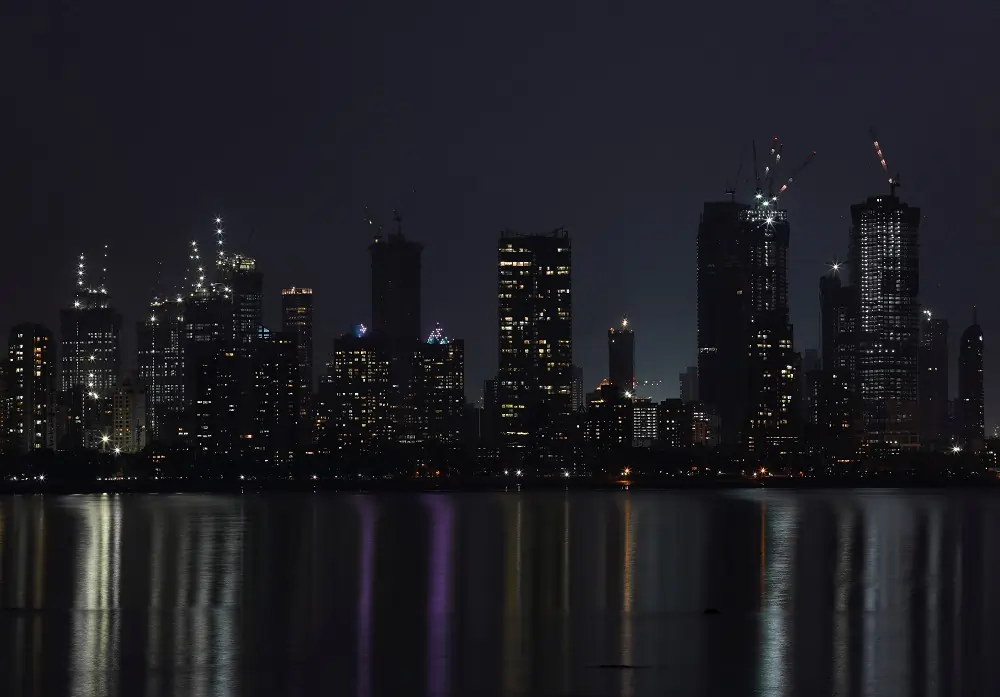 City skyline illuminated at night over water reflection.